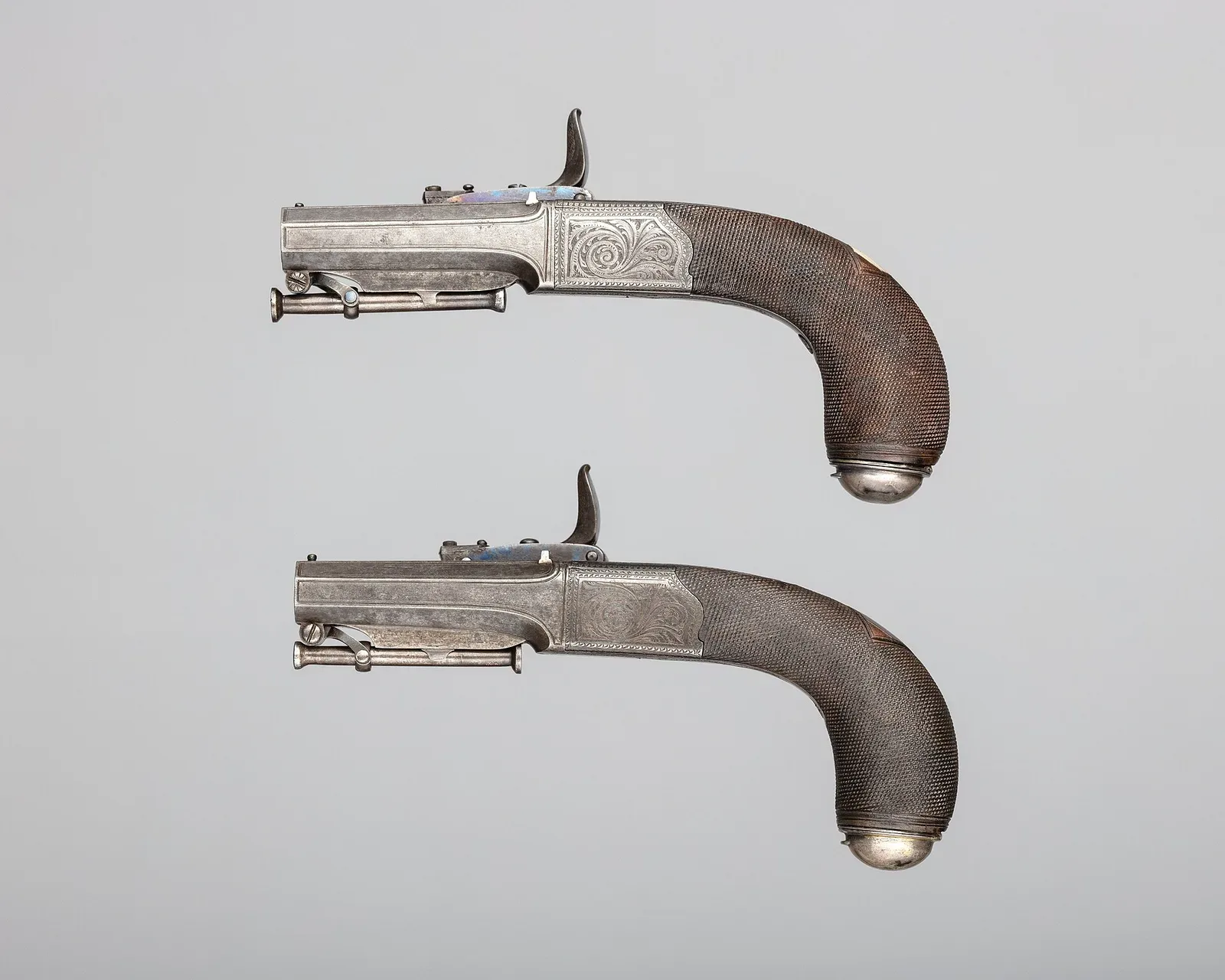 A pair of ornate flintlock-era pistols with sliding primer mechanisms, featuring detailed metalwork and wooden grips, representing Forsyth's patented percussion ignition design.