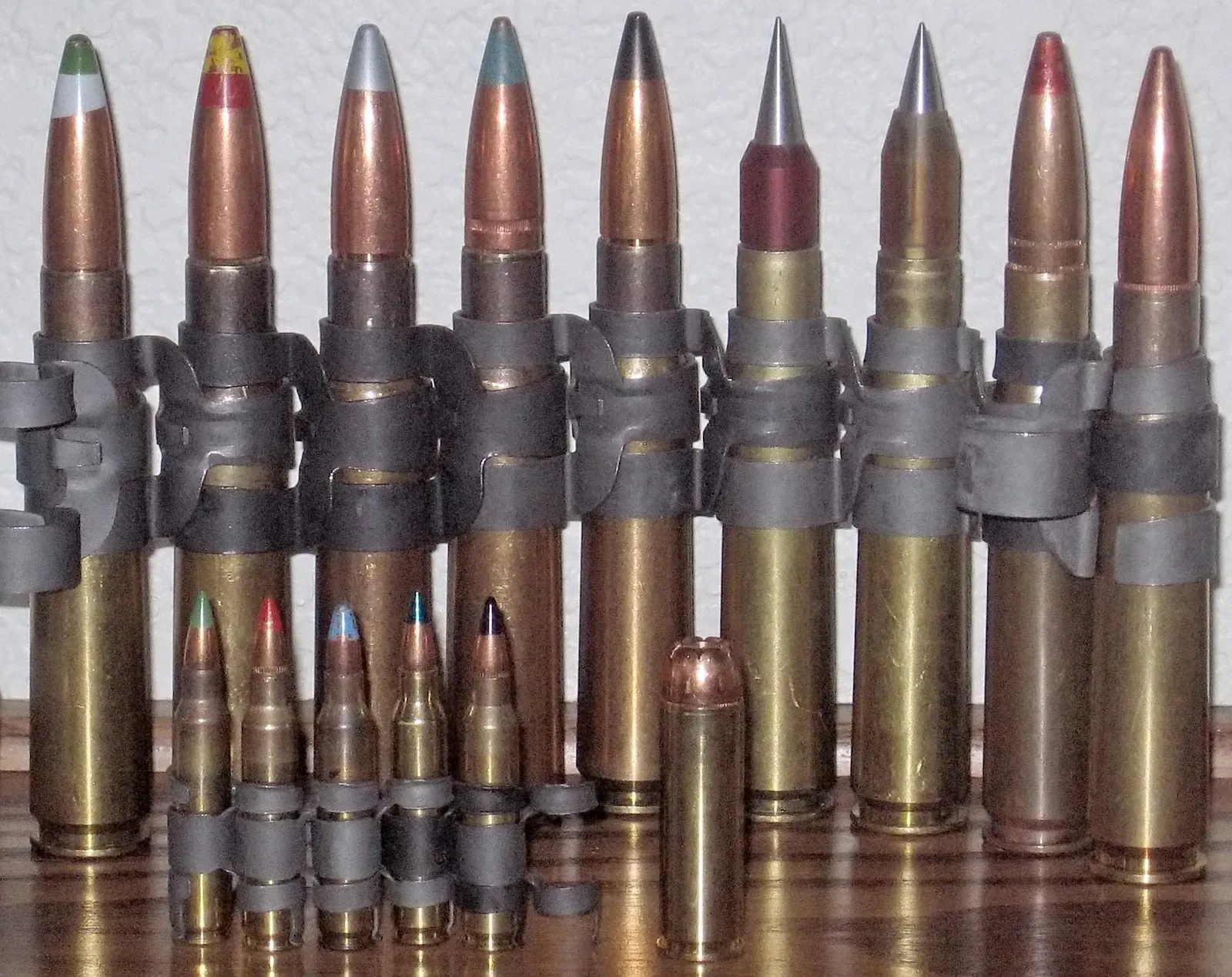 Four .50 BMG cartridges arranged in a row, showing from left to right: Mk211 Raufoss Multipurpose Round, standard ball round, tracer round, and armor-piercing variant, displaying different bullet construction and materials.