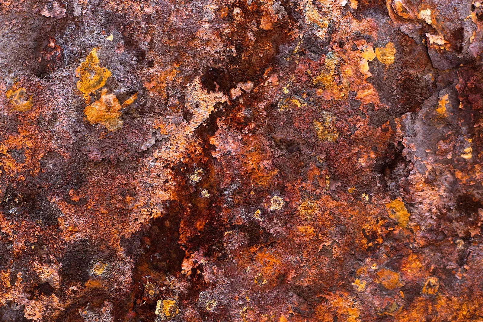 Close-up photograph of rust and oxidation on an iron surface, showing reddish-brown corrosion patterns and discoloration