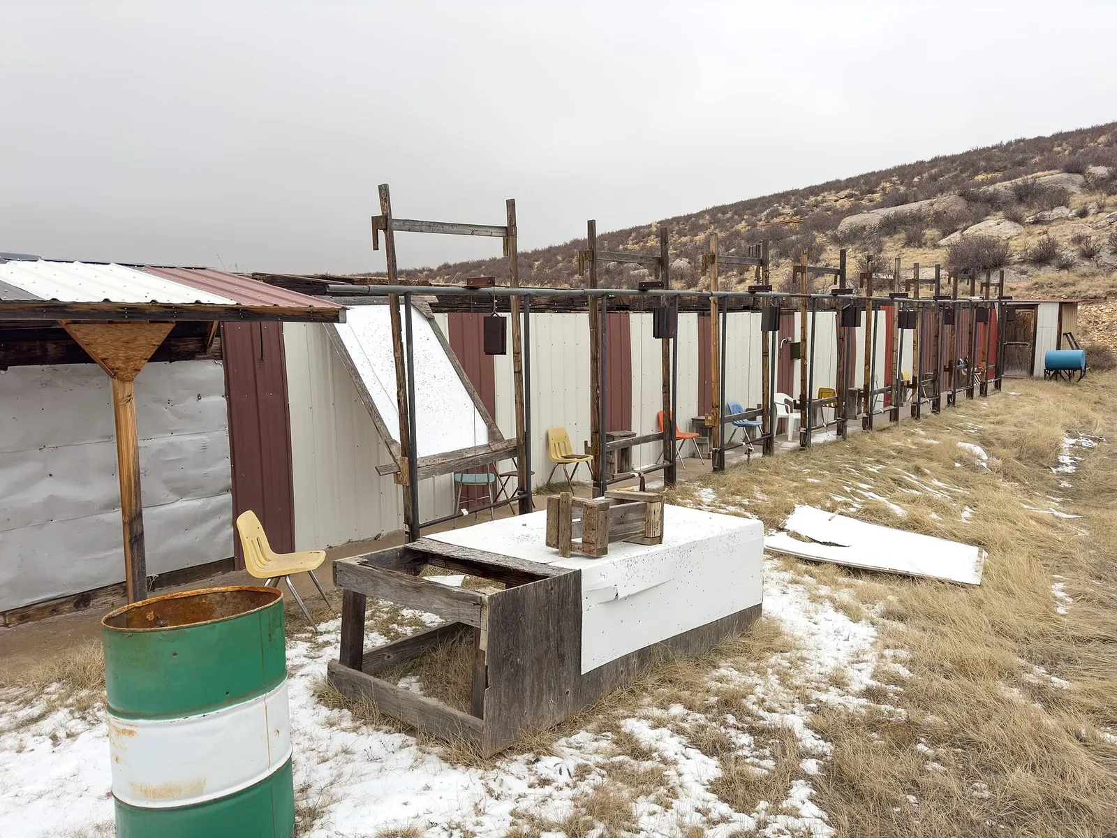Wide view of shooting pits at a rifle range with multiple shooting stations visible across an open valley landscape