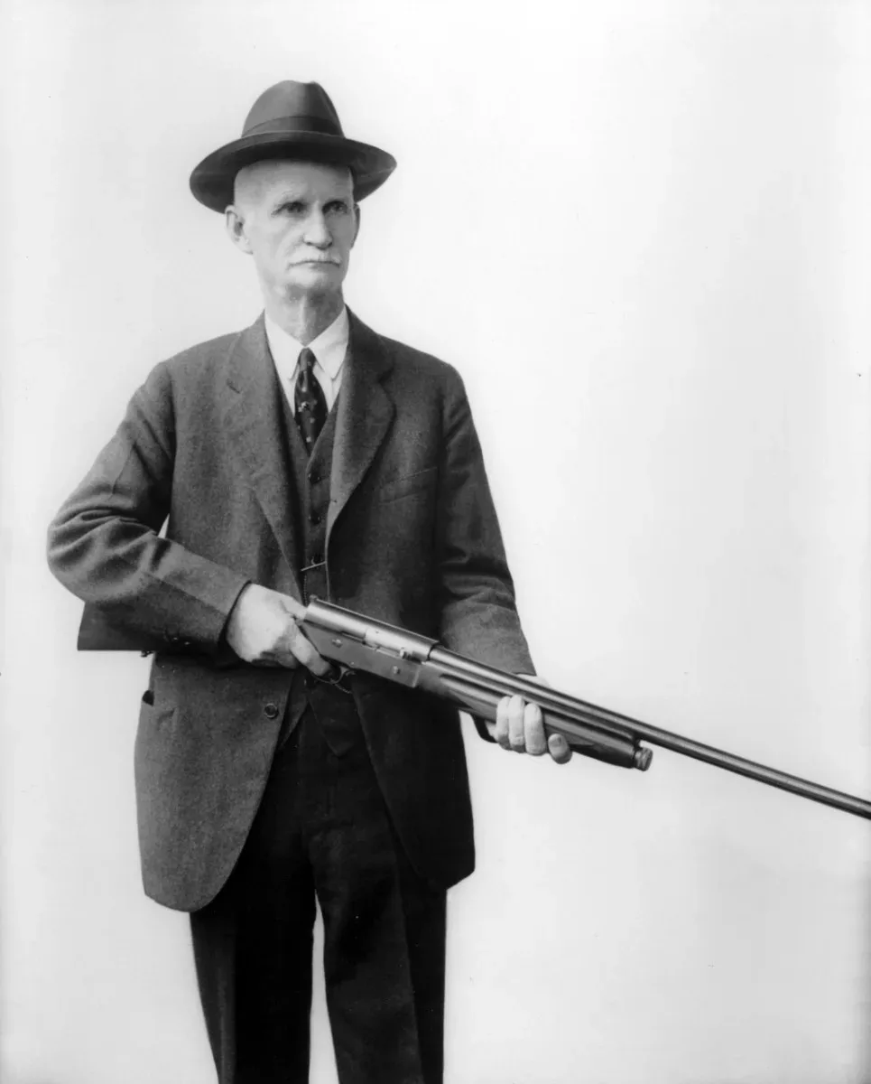 John Moses Browning standing and holding an Auto-5 semi-automatic shotgun, circa early 1900s.