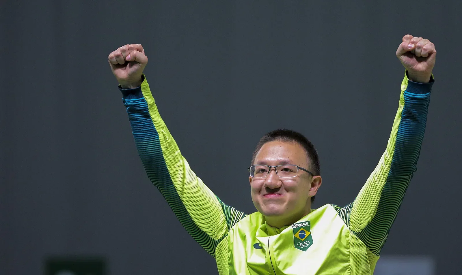 A pistol shooter in competition stance at the 2016 Olympic Games, aiming at a target from 10 meters distance during an air pistol event.