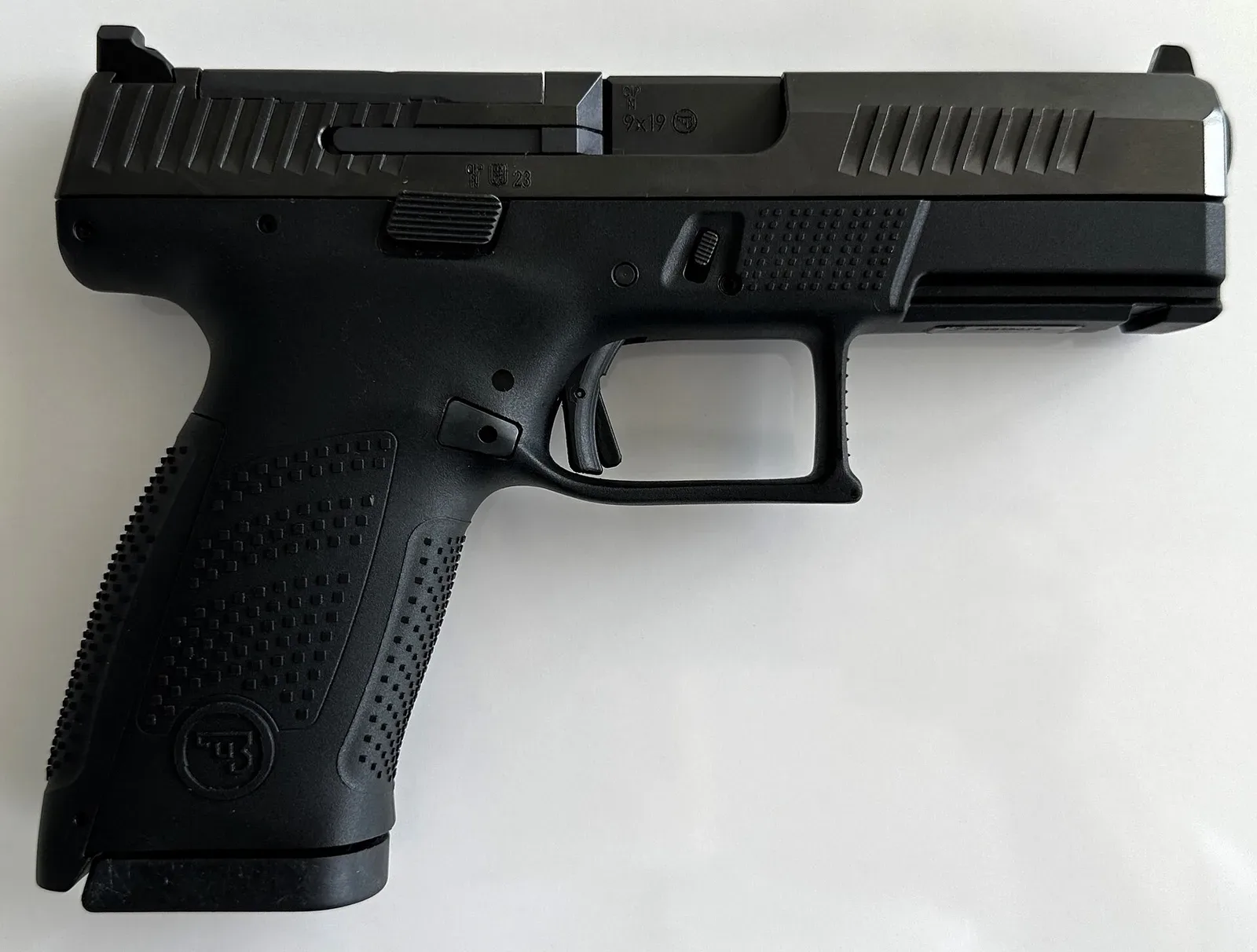 Side view of a CZ P-10 C semi-automatic pistol displayed against a neutral background, showing the right profile of the black polymer-framed handgun with visible slide serrations and controls