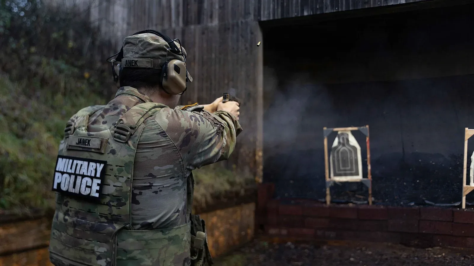 Law enforcement officer in tactical gear aiming a pistol at a shooting range during firearms training qualification