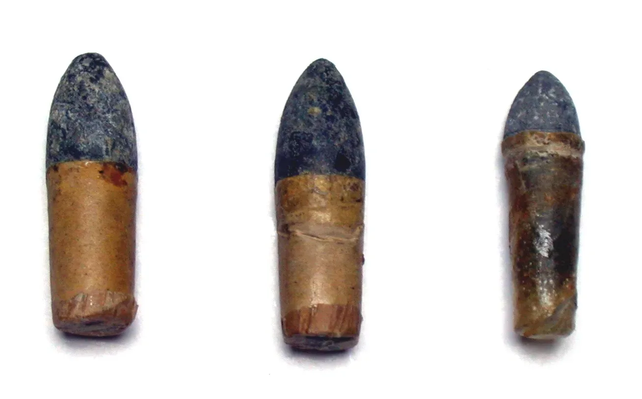 Two combustible Colt cartridges of .44 and .36 caliber, showing the paper-wrapped ammunition design with visible bullet and powder charge