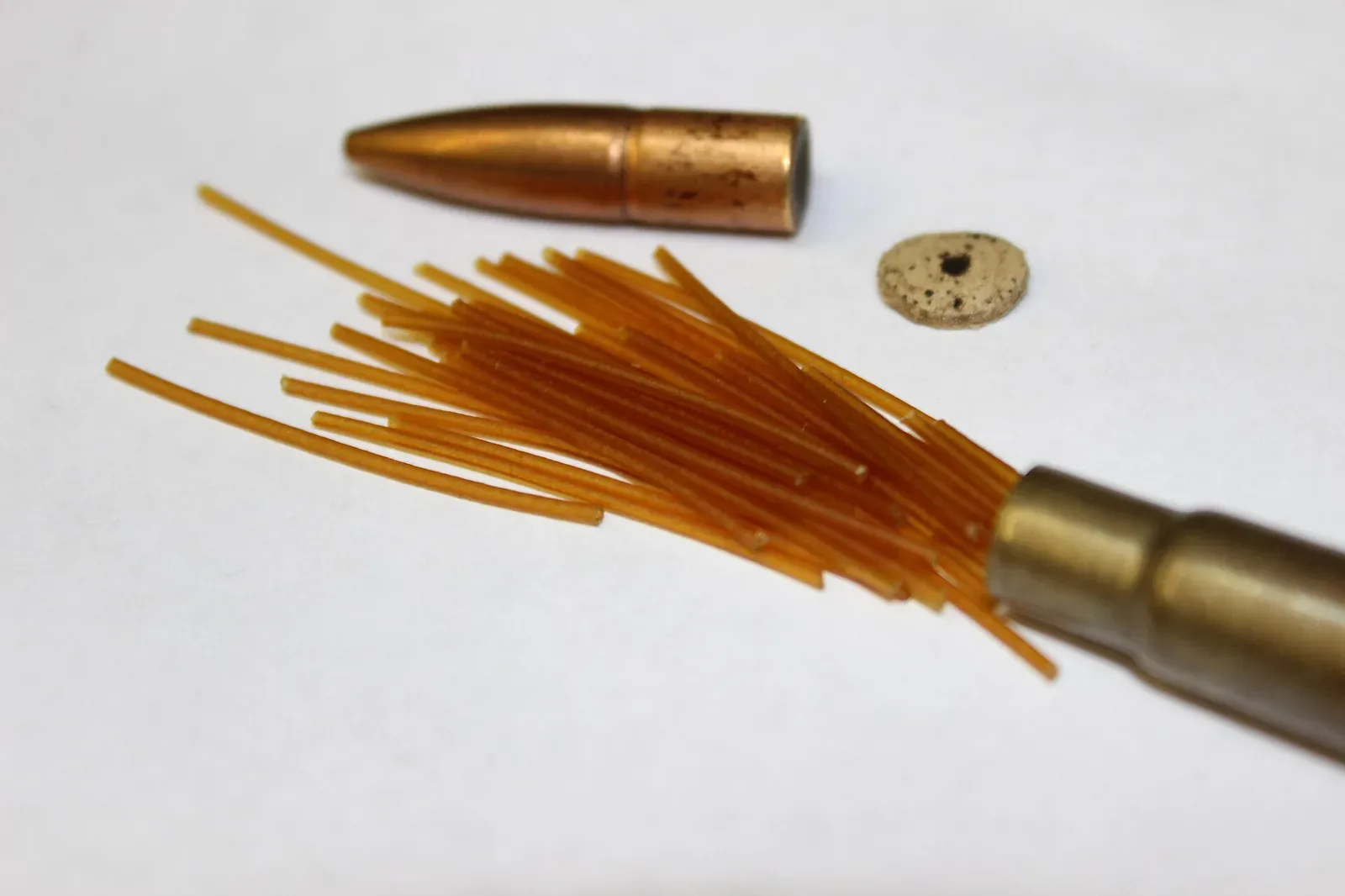 Close-up view of cordite filaments inside a .303 British rifle cartridge, showing the characteristic string-like propellant geometry.