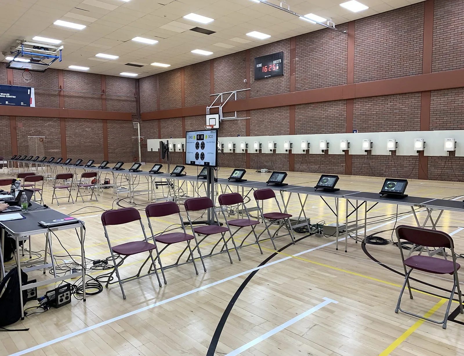 Shooters at firing stations during the 2022 European Commonwealth Shooting Championships, with multiple competitors visible at the 10-meter range setup.