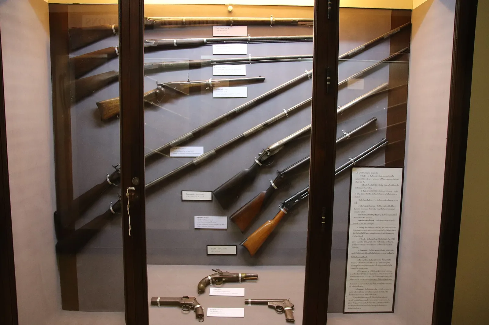Multiple historical firearms of varying designs and eras displayed together in a museum collection, showing the diversity of firearm types and mechanisms.