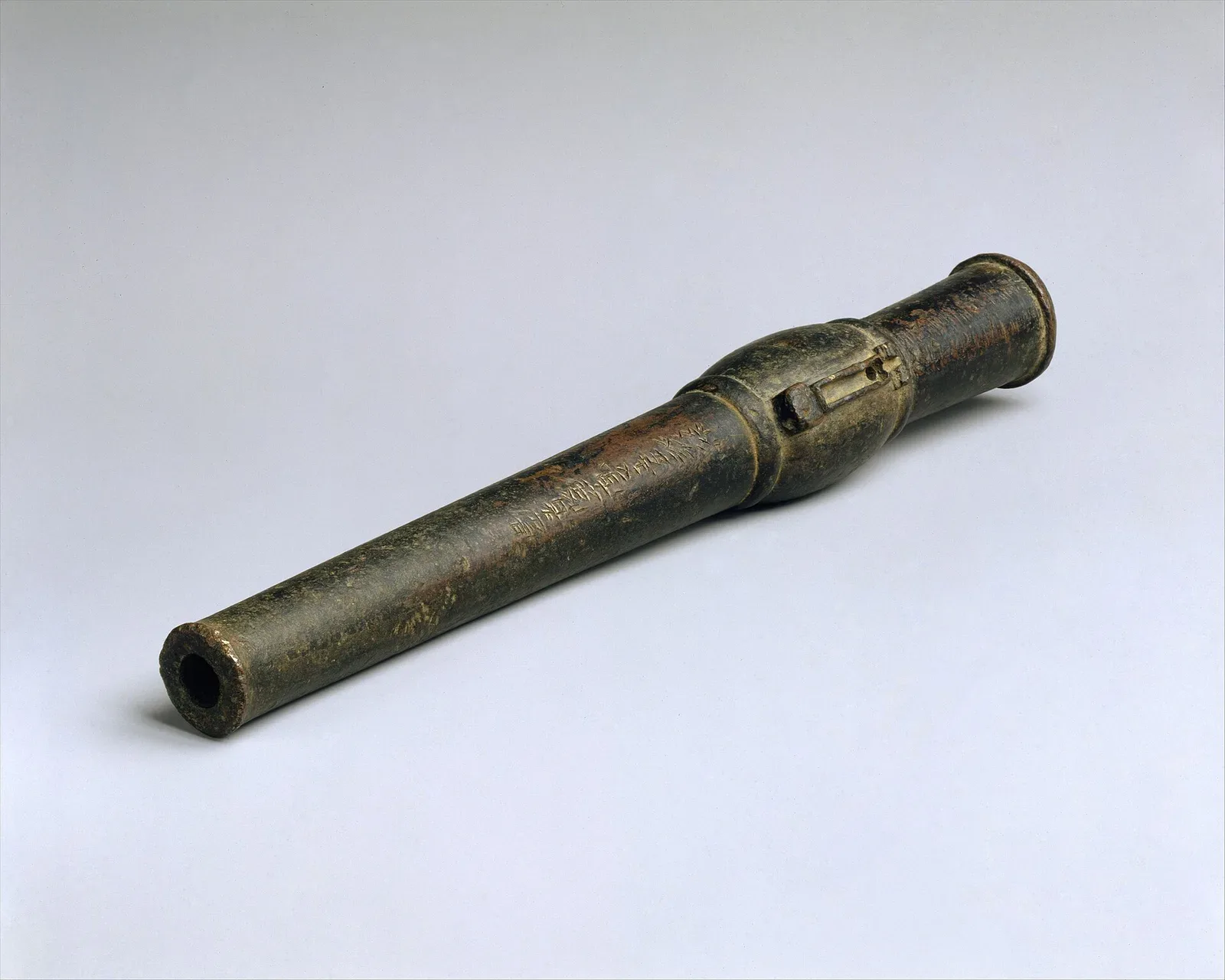 A Chinese hand cannon (chong) with a bronze barrel and wooden stock, displayed as a complete artifact. The barrel appears to be reinforced with metal bands, and the overall construction shows early firearm design with a touch-hole for ignition.