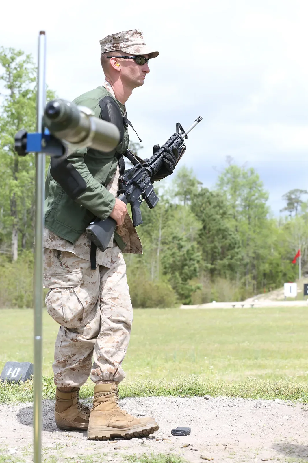 Marine Corps shooter in prone position wearing shooting jacket and sling while aiming rifle during competition