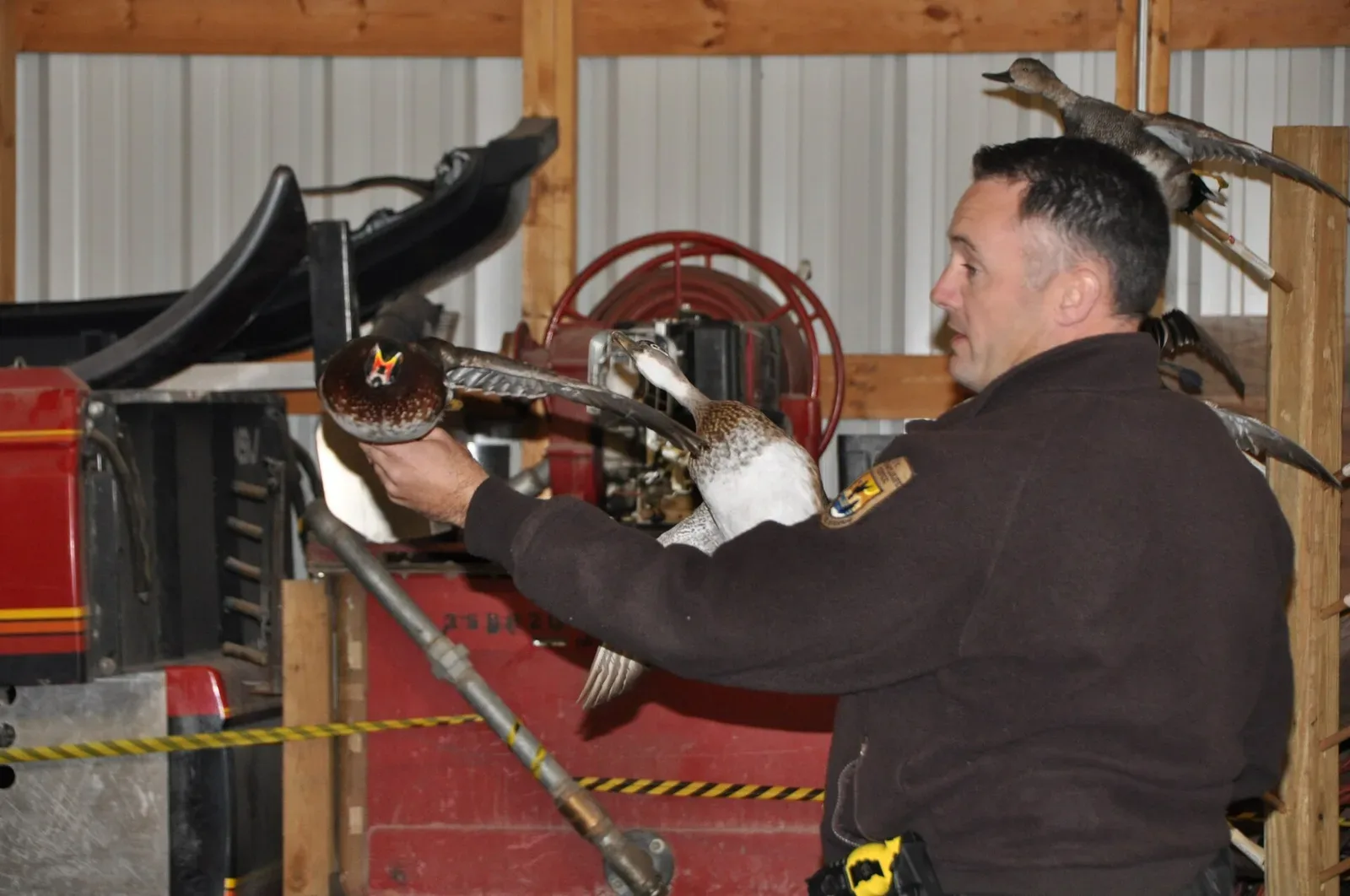 An instructor demonstrating duck species identification to a group of young hunters during an outdoor field training session.