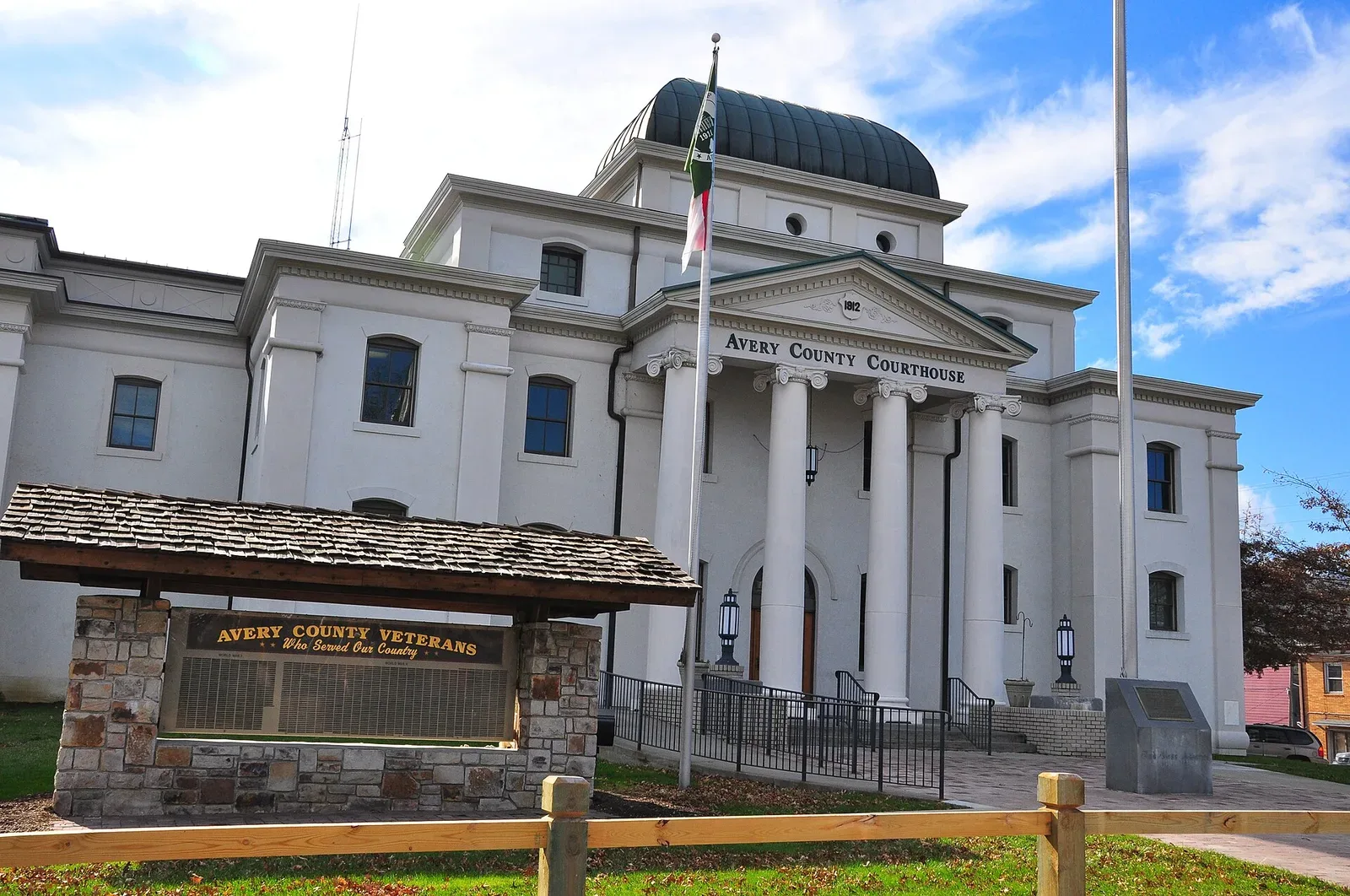 A two-story brick courthouse building with classical architectural features, situated in a town setting with bare trees visible in the foreground.