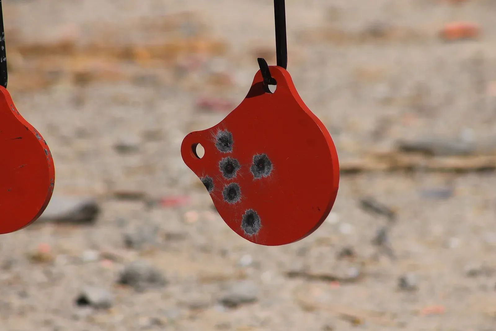 Multiple steel targets hanging from a frame at an outdoor shooting range, showing various target shapes used in practical shooting competitions.