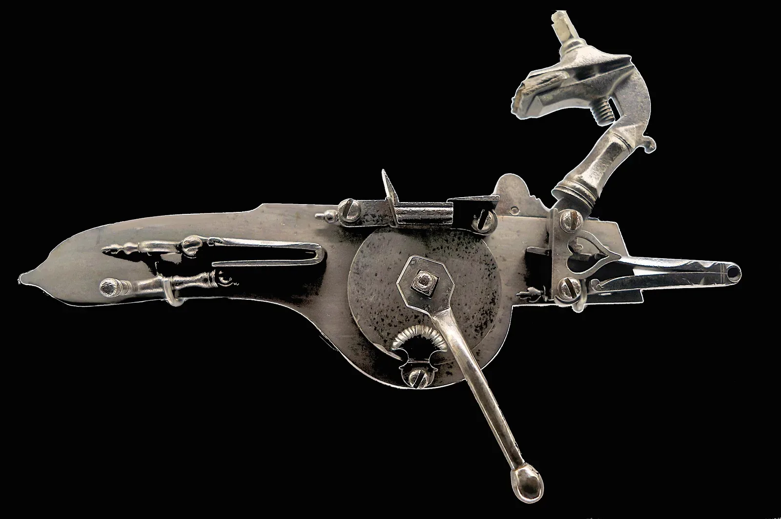 Close-up photograph of the internal firing mechanism of a flintlock musket, showing the steel components including the cock, frizzen, and mainspring assembly
