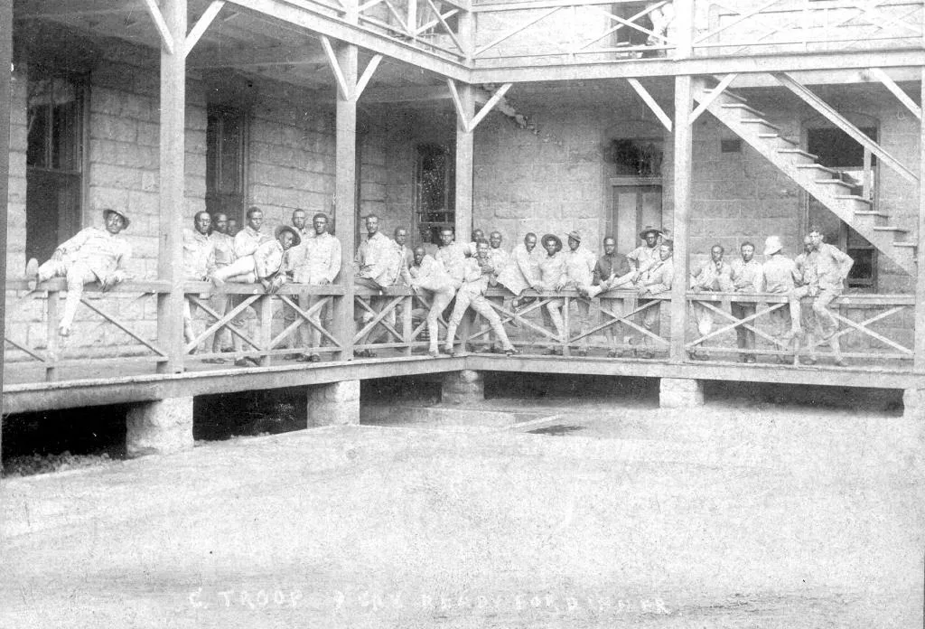 Buffalo soldiers in military uniforms posing outside their barracks at Fort Riley