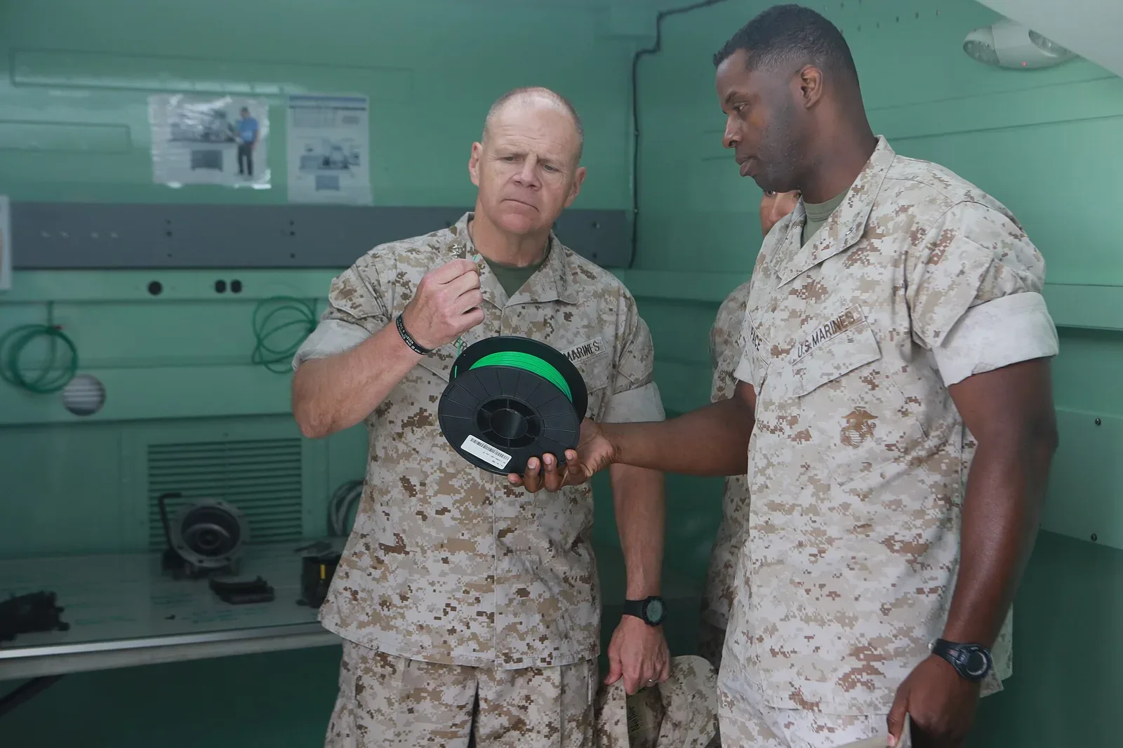 A Marine Corps officer operating a large-format 3D printer, demonstrating additive manufacturing equipment in an institutional setting.