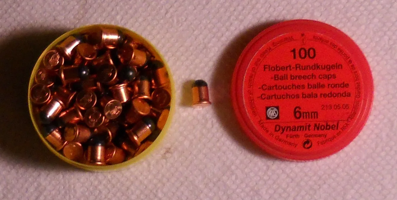 Photograph of a .22 BB Cap rimfire cartridge next to its original container