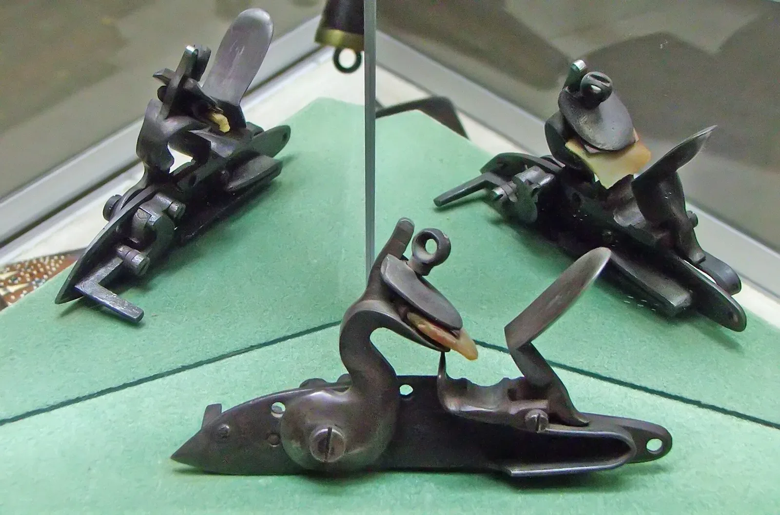 Detailed view of a flintlock mechanism showing the hammer, frizzen, and firing pan components of a flintlock firearm.