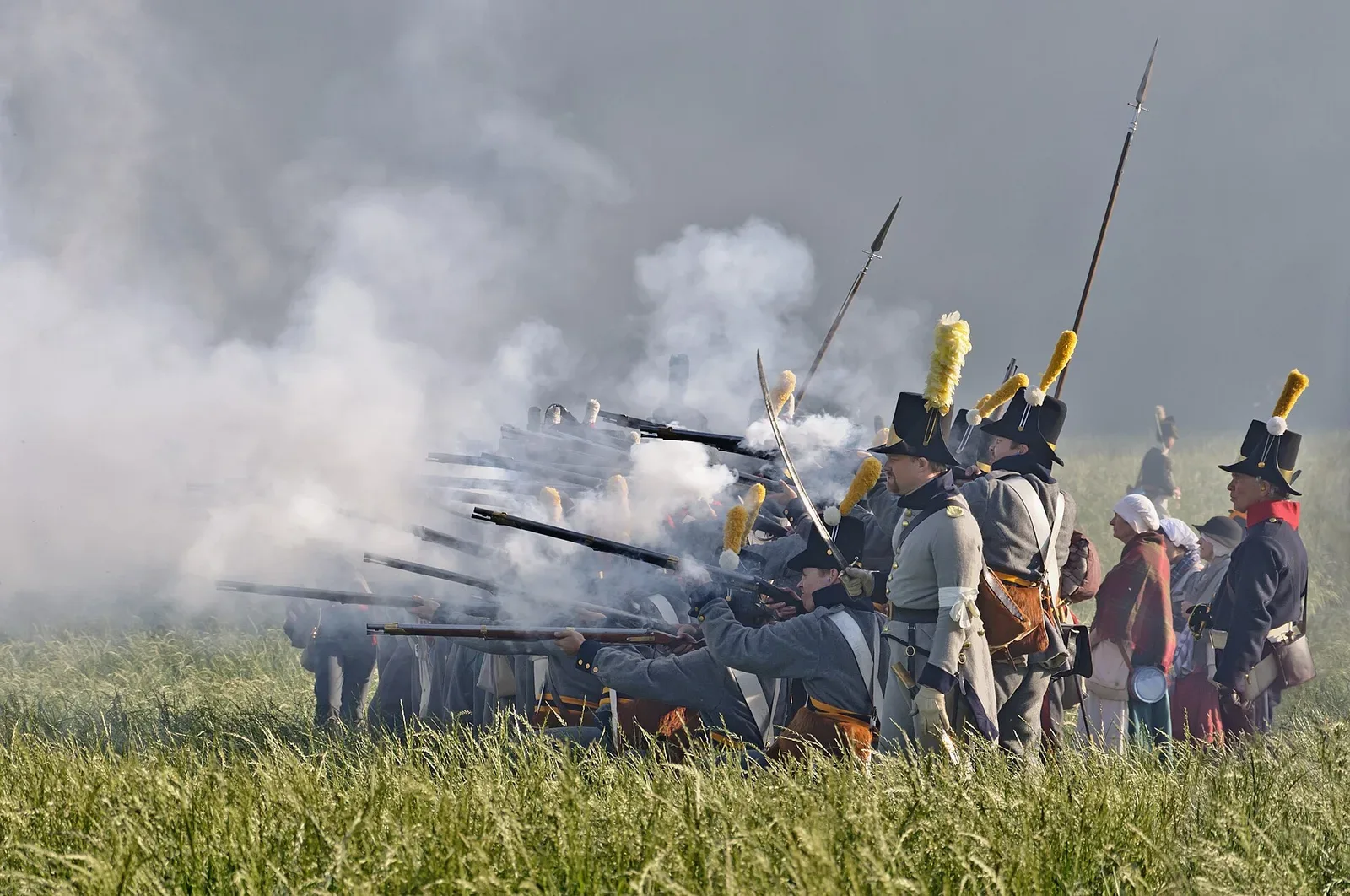 Civil War era soldiers in period military uniforms firing muskets during a battle reenactment at Waterloo 1815 reconstitution in 2011, demonstrating historical combat techniques and equipment.