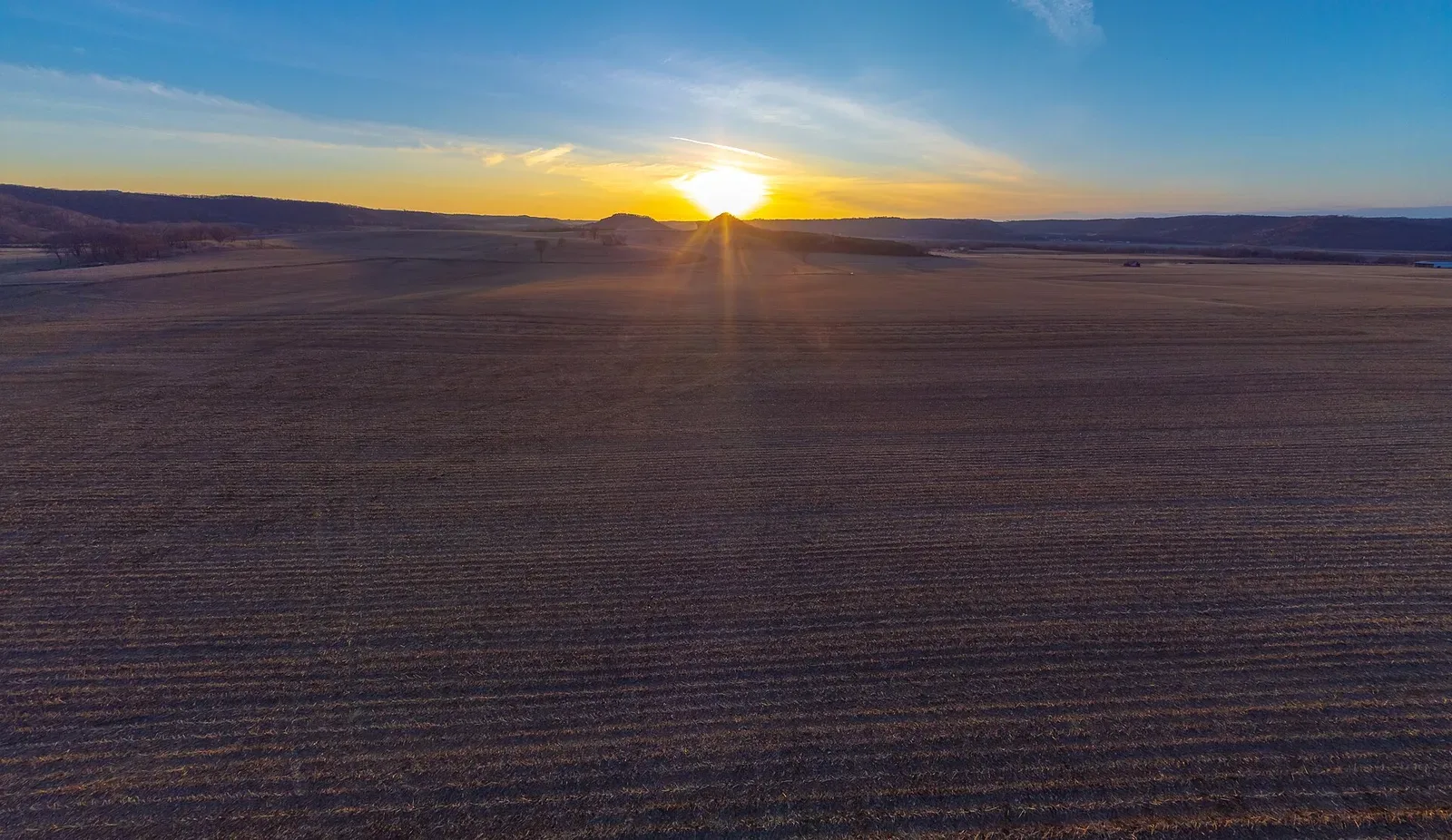 Expansive Iowa landscape showing rolling terrain with agricultural fields and vegetation under a cloudy sky
