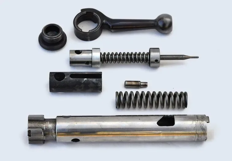 Disassembled bolt of a Swing Mk4 Target Rifle, showing separated components including the firing pin spring and other internal parts laid out for inspection