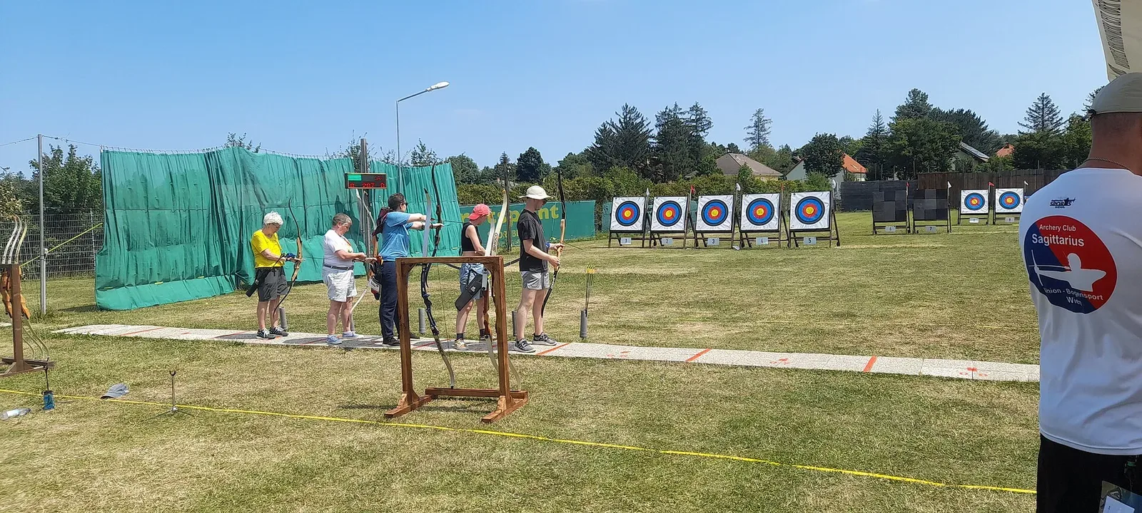 Archers competing at the EuroGames 2024 archery competition, with multiple participants drawing bows at their targets