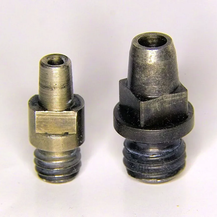 Close-up view of a percussion cap fitted onto a nipple, showing the small metal cup design and how it seats on the threaded post.