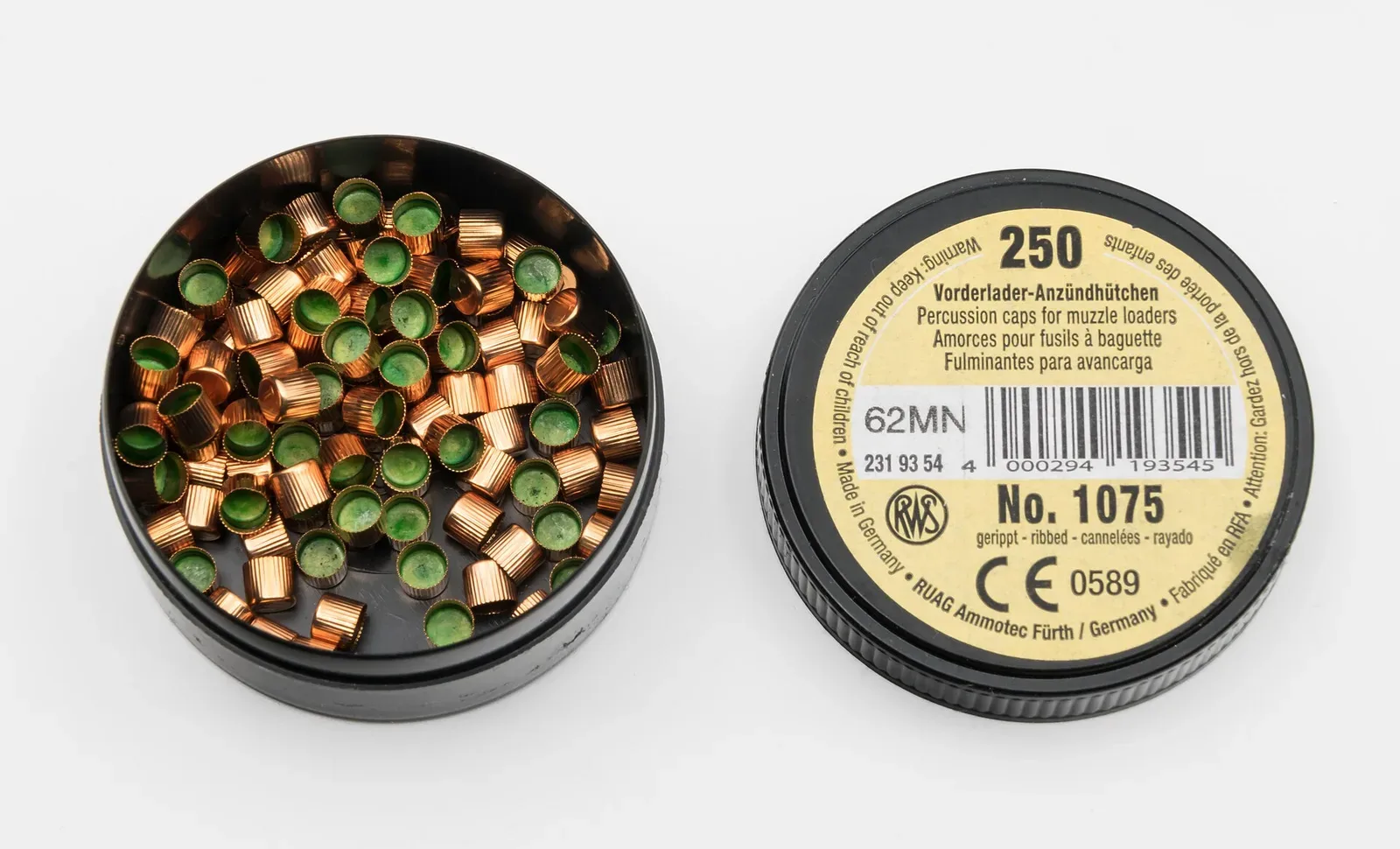 Close-up photograph of RWS 1075 percussion caps showing the distinctive copper cylindrical casings and their internal composition