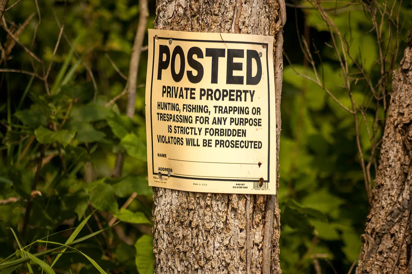 A posted 'No Trespassing' sign mounted on a wooden post or structure in the United States