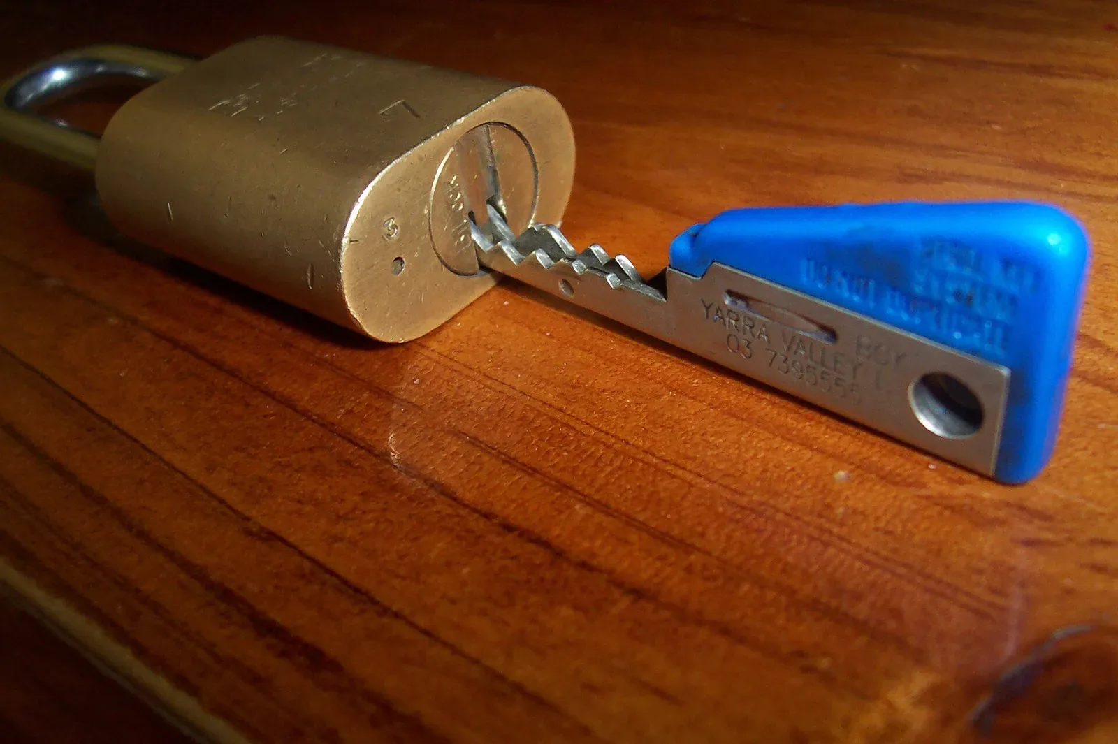A Bilock high-security dual-barrel padlock with two cylindrical keyholes, mounted on a security fence