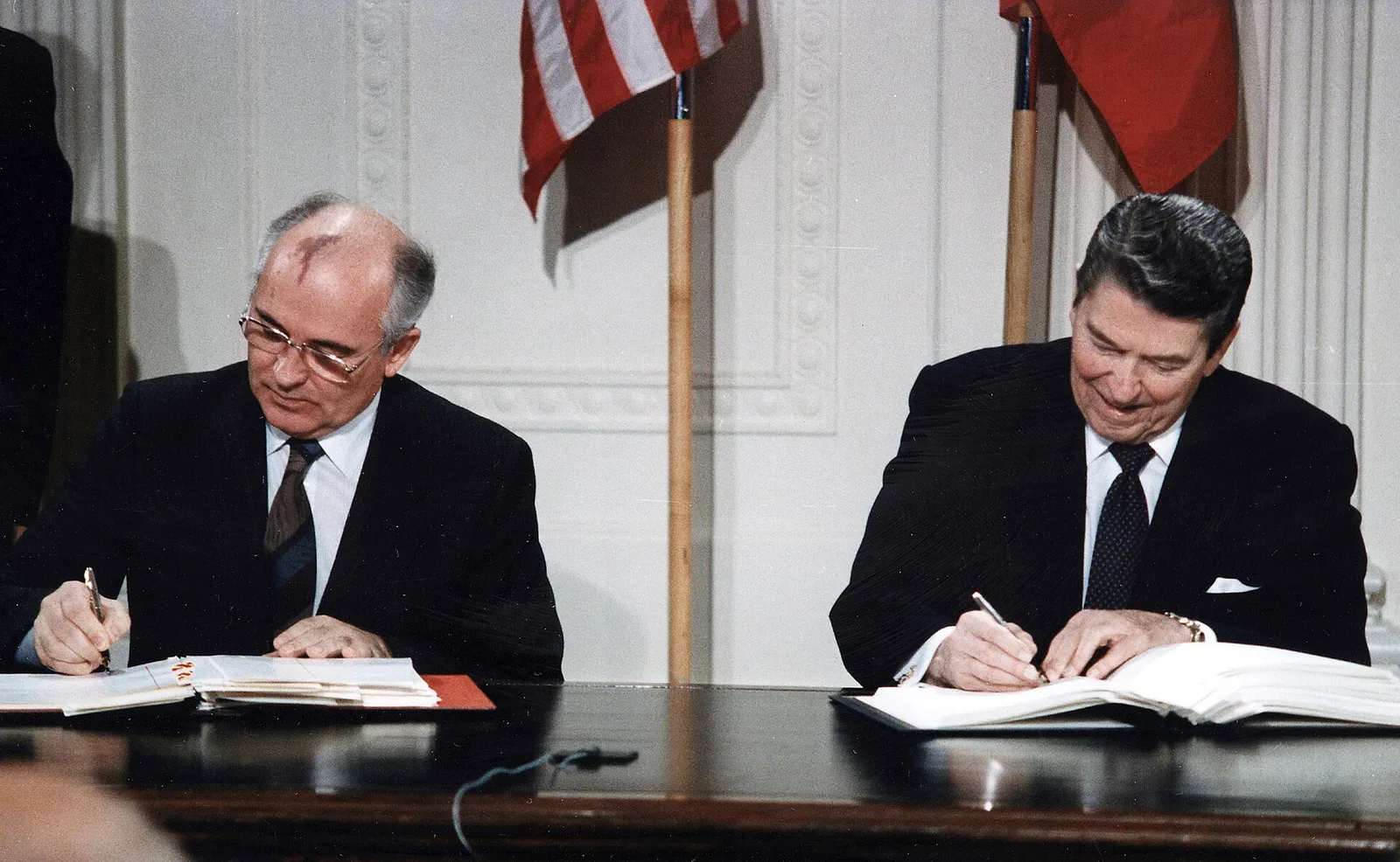 Ronald Reagan and Mikhail Gorbachev signing a document at a formal diplomatic meeting