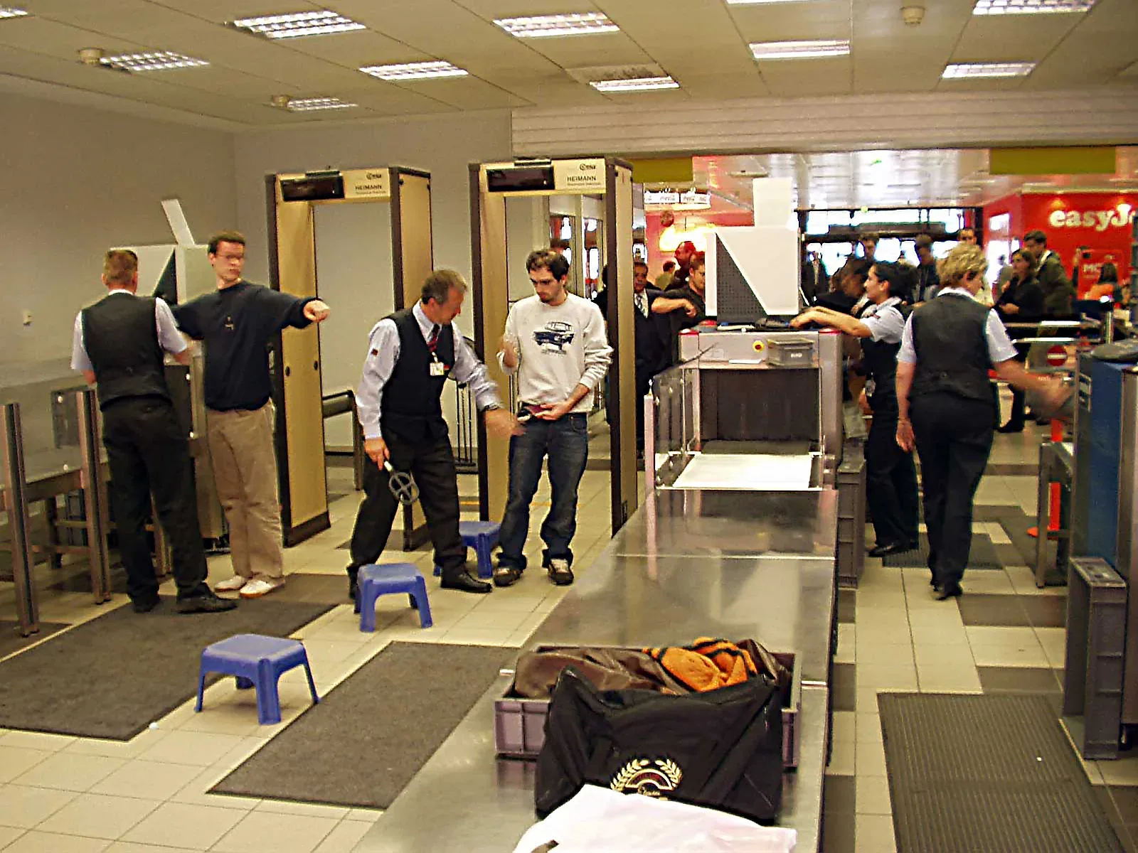 Security screening checkpoint at an airport with metal detection equipment and security personnel
