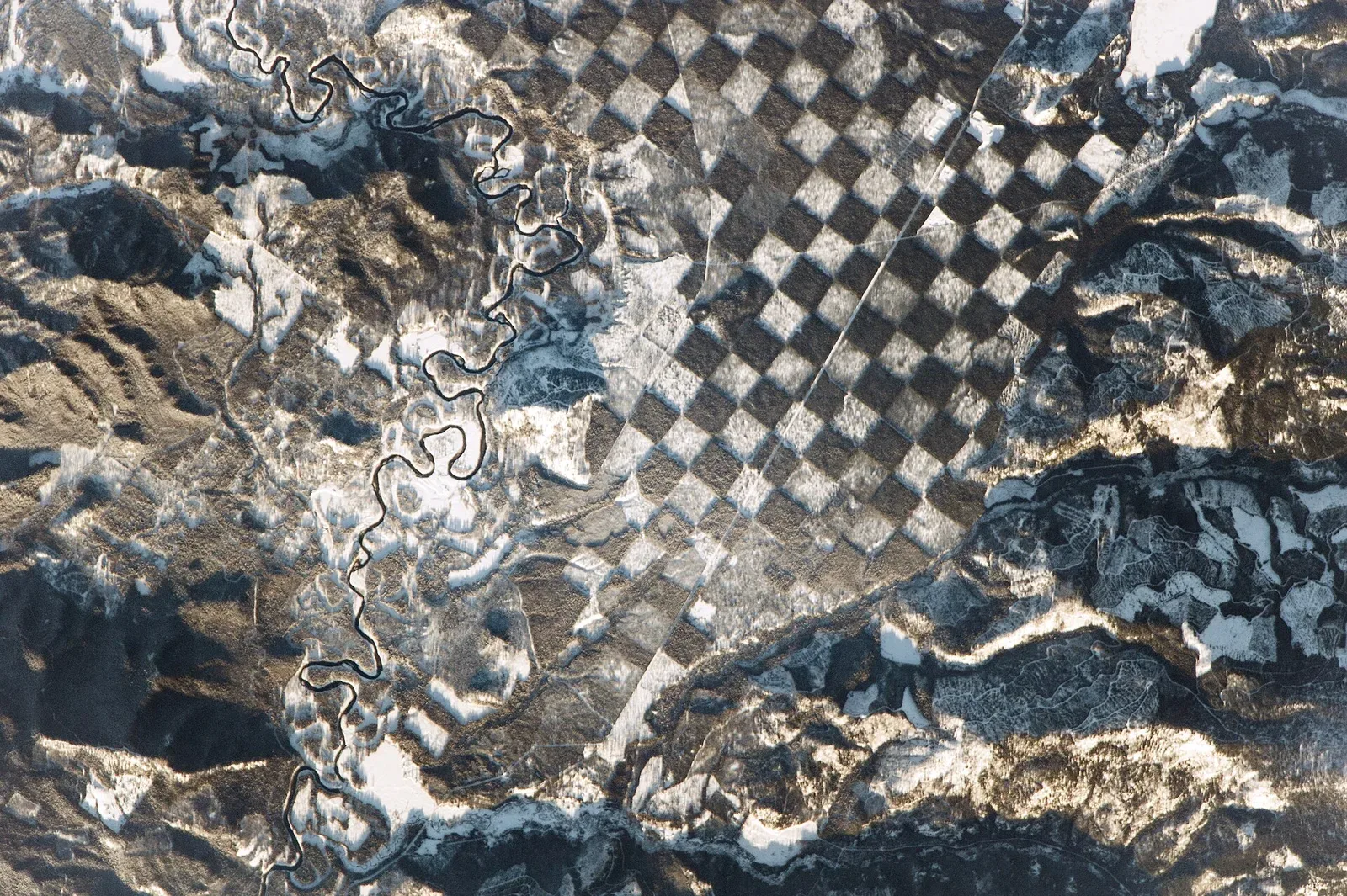 Satellite photograph of Idaho showing a distinctive checkerboard pattern of forested and cleared land parcels across the state's landscape.